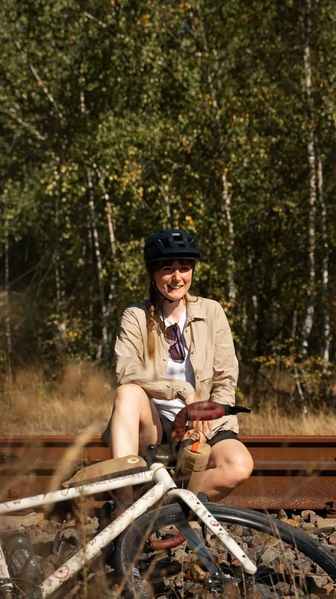 A woman is sitting on the tracks, whilst the veloheld.iconX in the Female Explorer Edition is resting on the ballast
