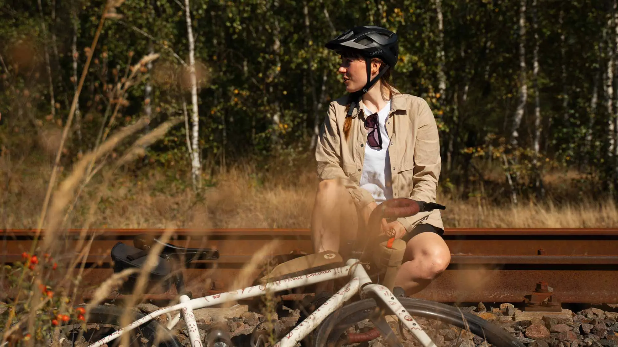 A woman is sitting on old rails and a gravel bike from veloheld lies in front of it