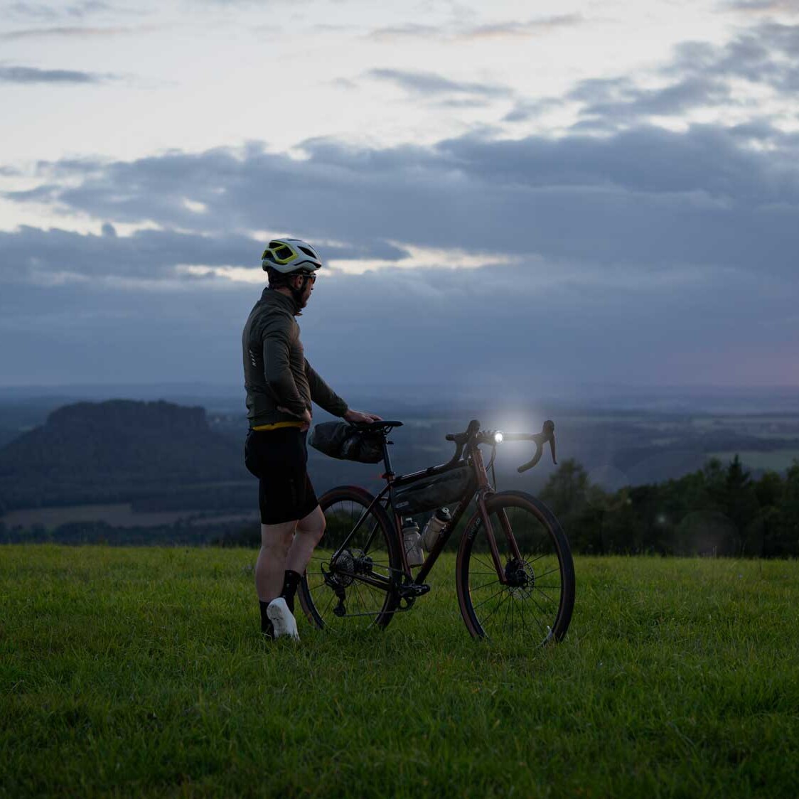 veloheld.iconX gravel bike on a meadow in semi-darkness with bright headlights