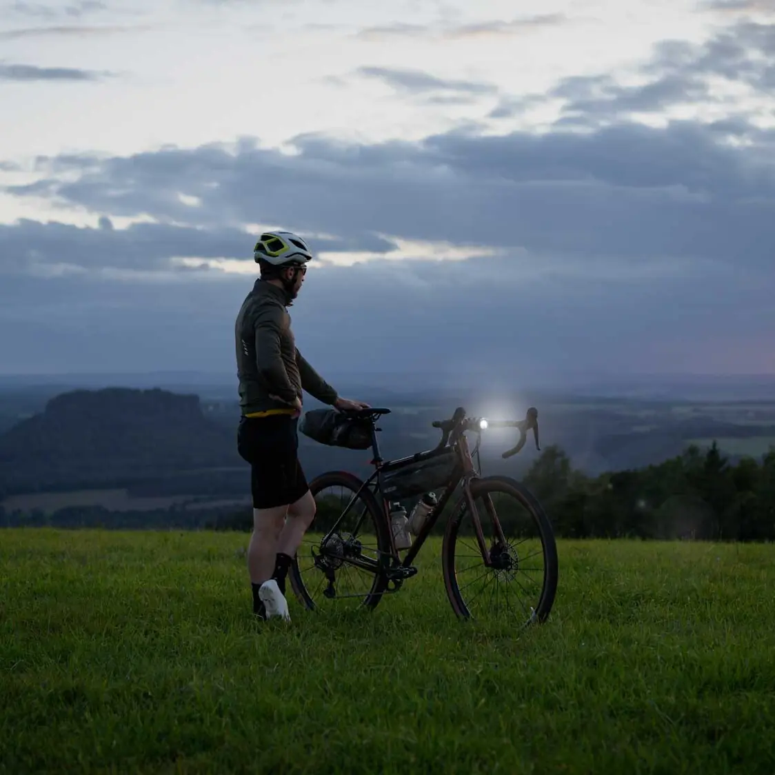 veloheld.iconX gravel bike on a meadow in semi-darkness with bright headlights