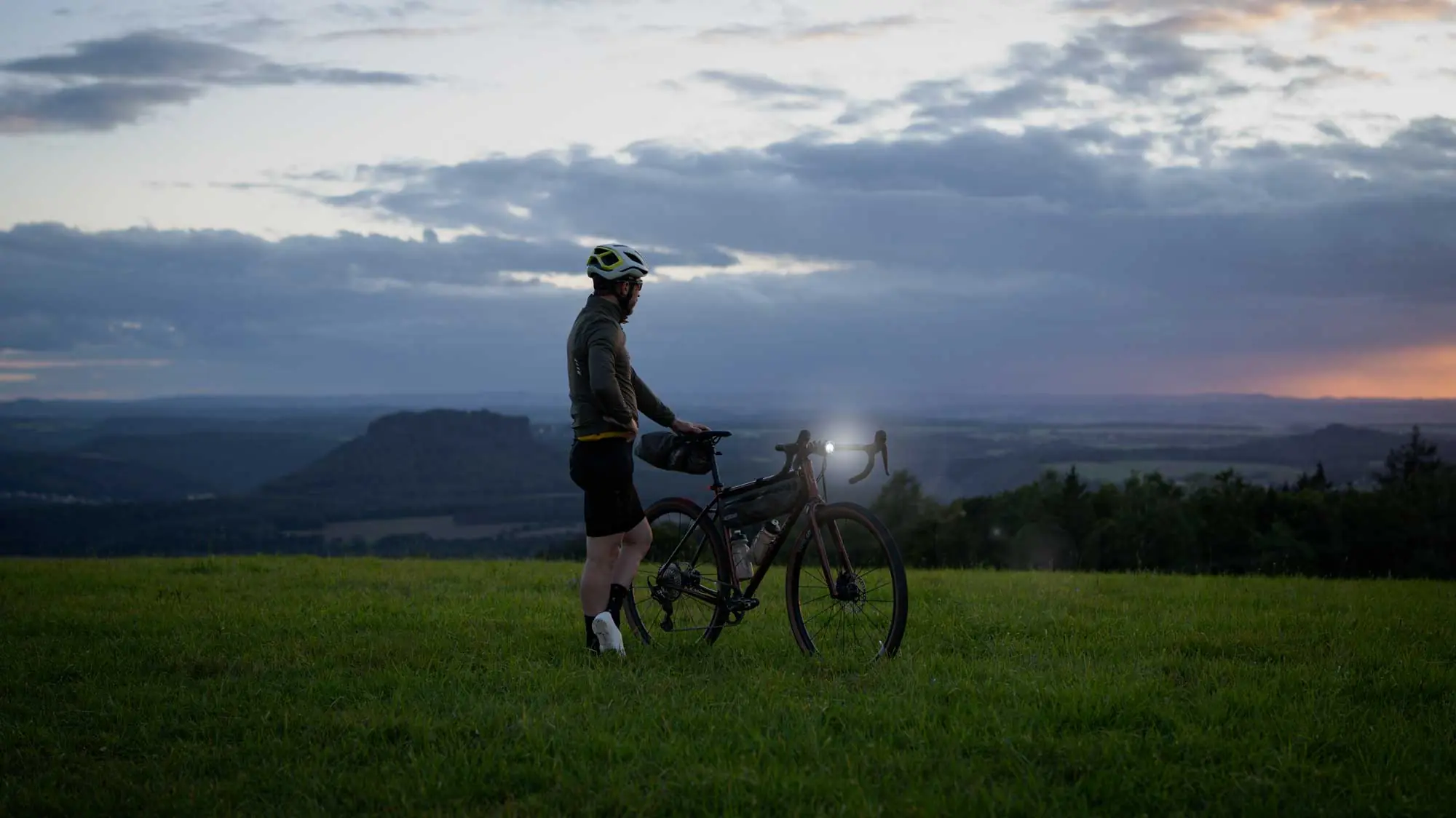 veloheld.iconX gravel bike on a meadow in semi-darkness with bright headlights