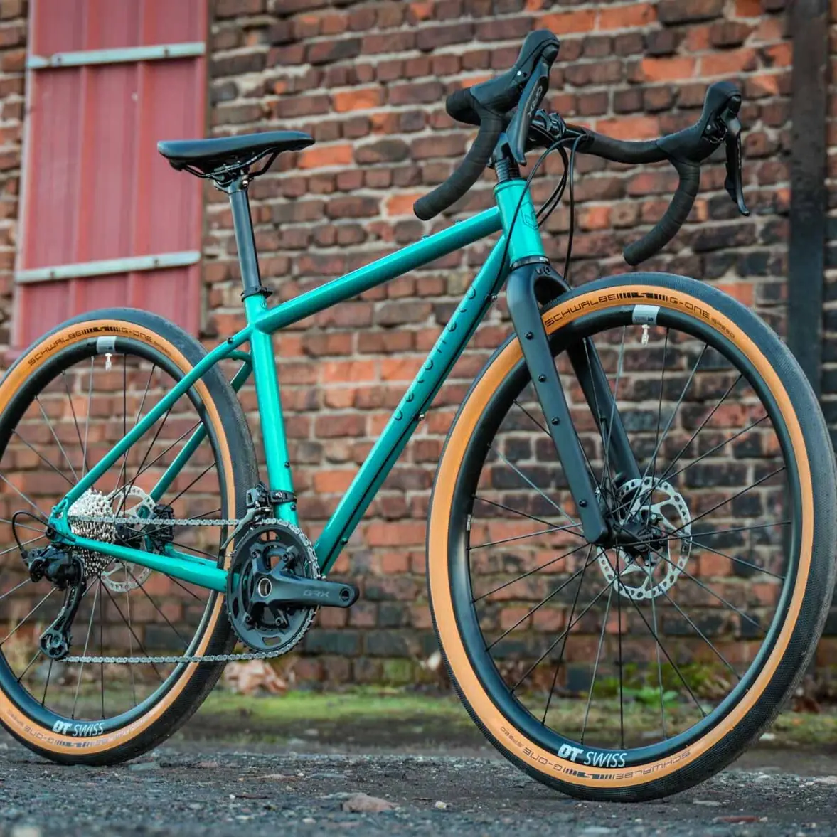 Gravel bike by veloheld in blue-green in front of a brick wall