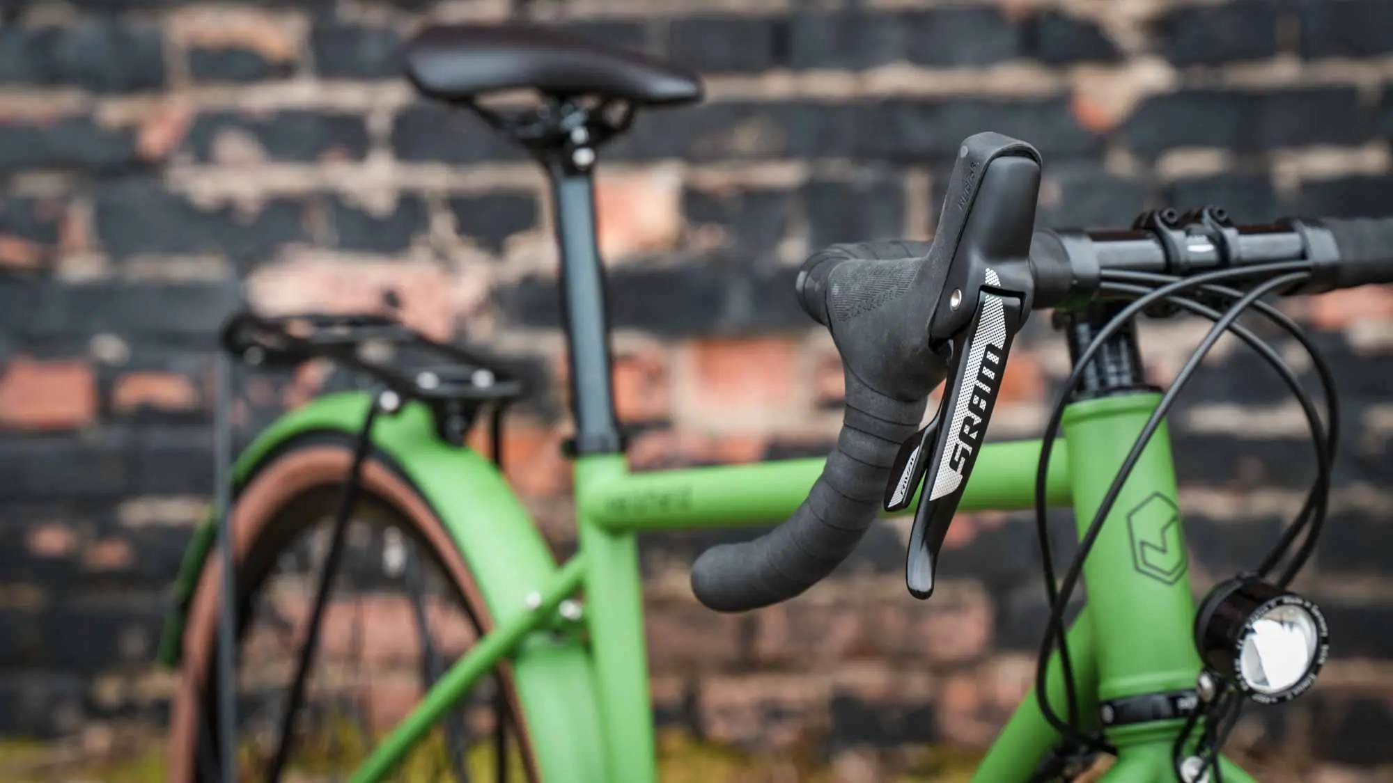 veloheld.alleyX Tourist in grass green, cockpit and top tube in front of brick wall