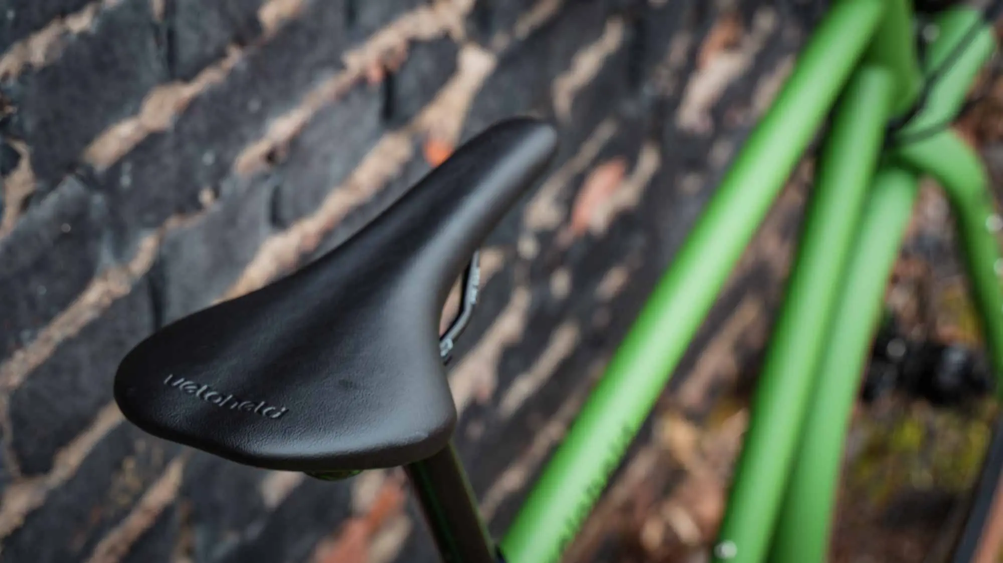 veloheld.alleyX Tourist in grass green, saddle detail in front of brick wall