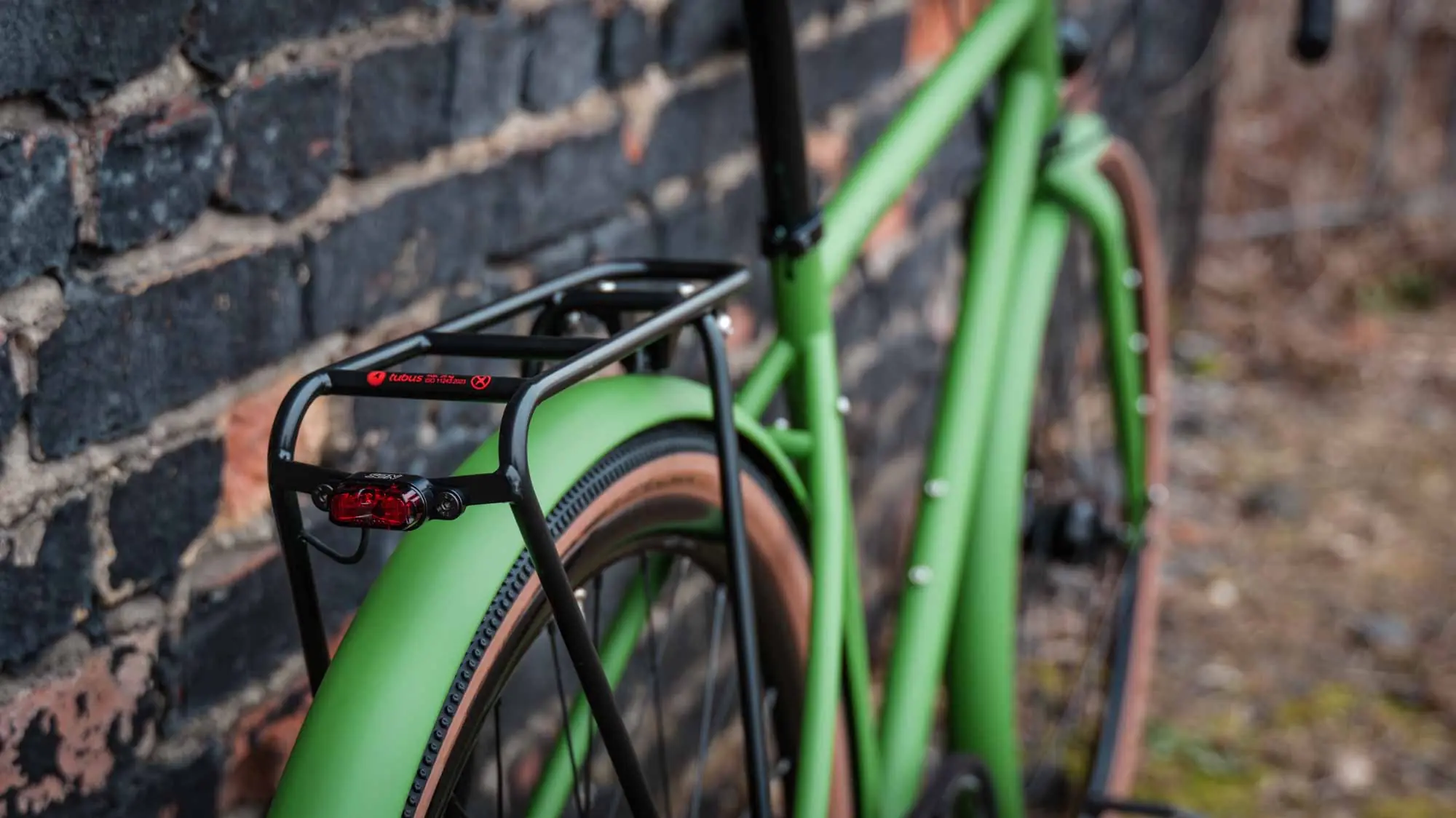 veloheld.alleyX Tourist in grass green, luggage rack and rear light detail in front of brick wall