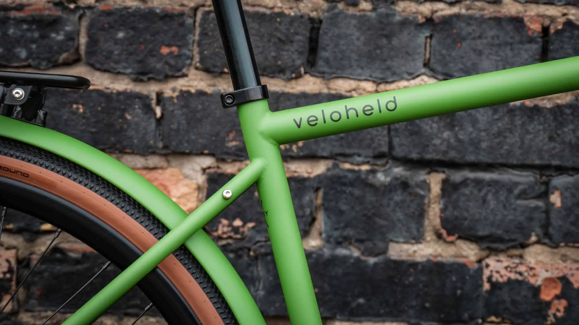 veloheld.alleyX Tourist in grass green, frame detail with logo in front of brick wall