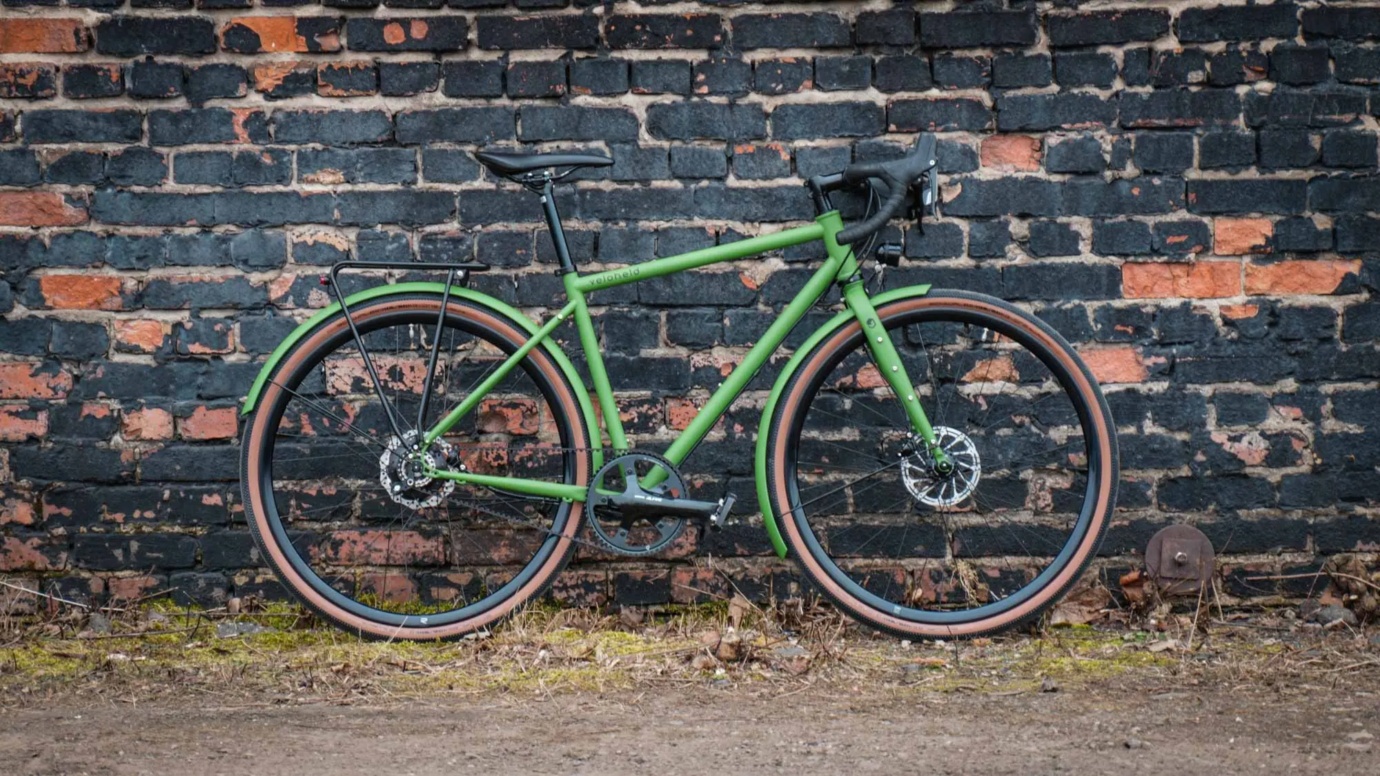 veloheld.alleyX Tourist in green stands as a complete bike for a stone wall outside