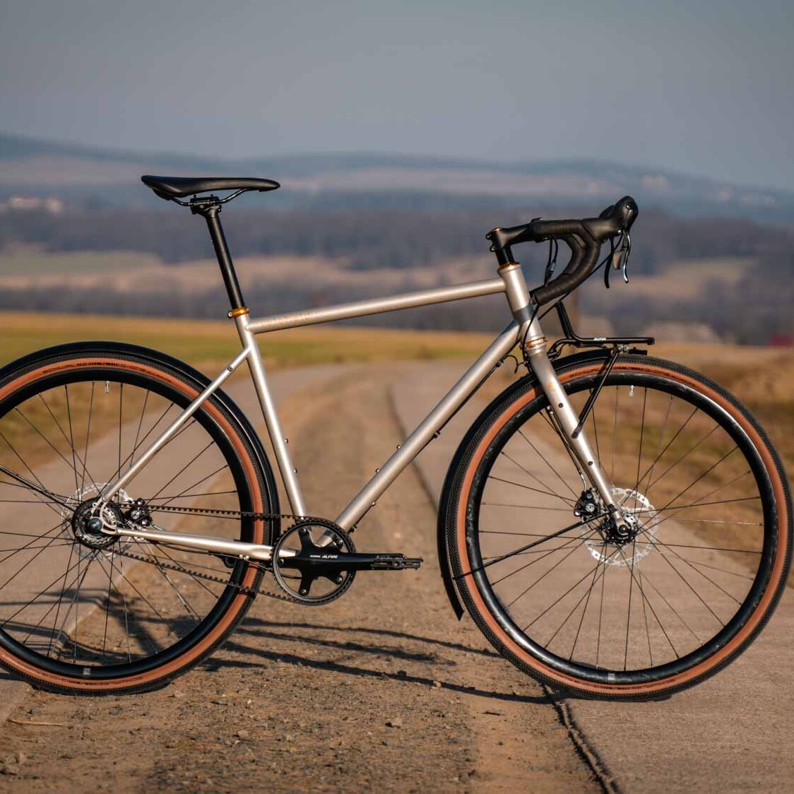 veloheld alleyX gravel bike in Roman bronze on an open country road, side view in the evening light