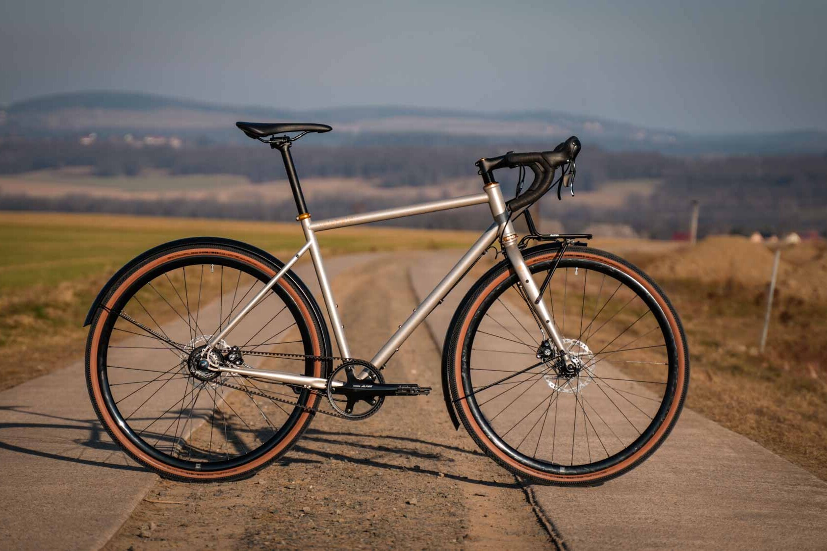 veloheld alleyX gravel bike in Roman bronze on an open country road, side view in the evening light