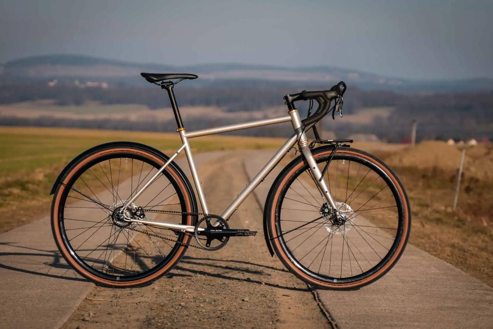 veloheld alleyX gravel bike in Roman bronze on an open country road, side view in the evening light