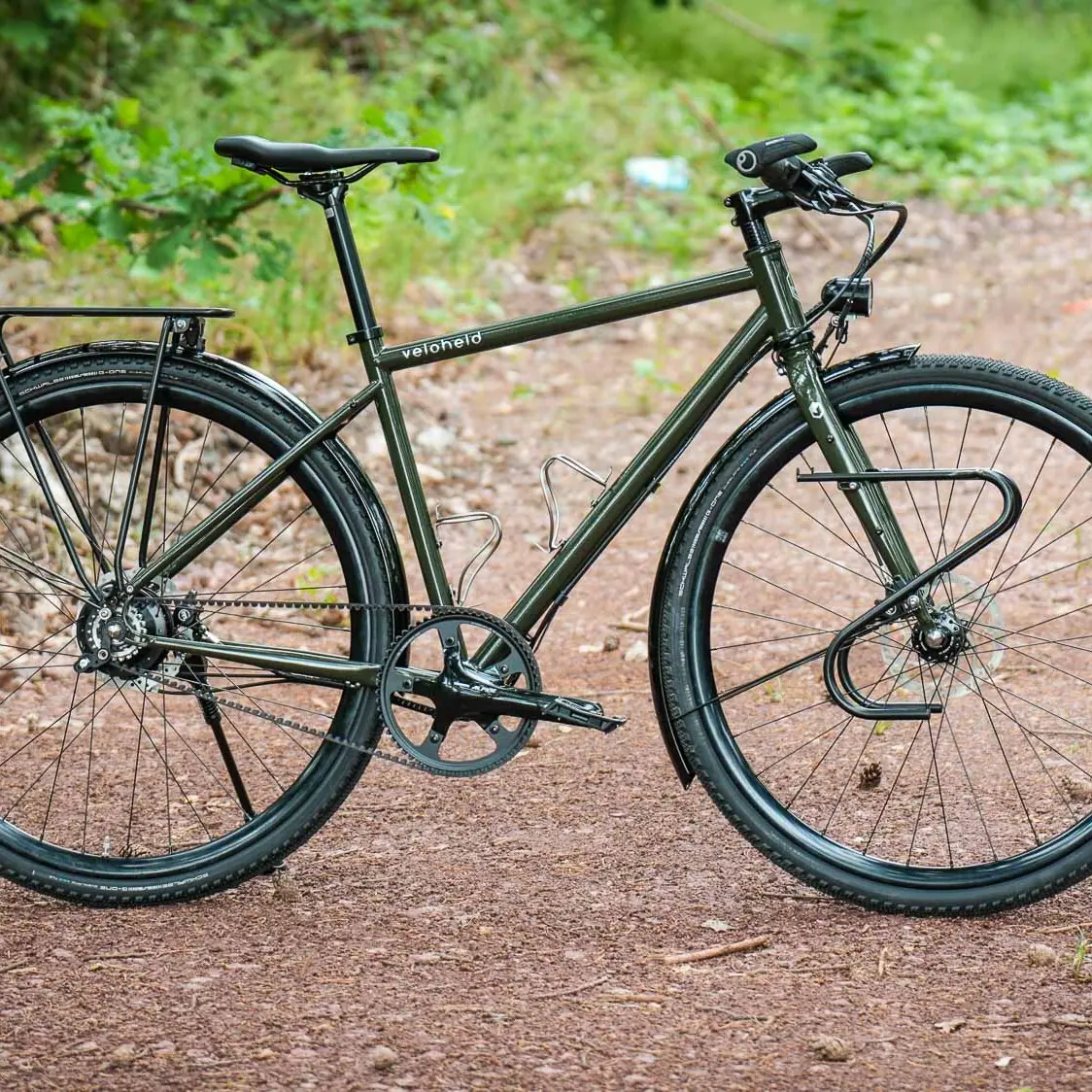 veloheld.alleyX Complete bike with Rohloff hub gears, mudguards and luggage rack as full view on a forest path.