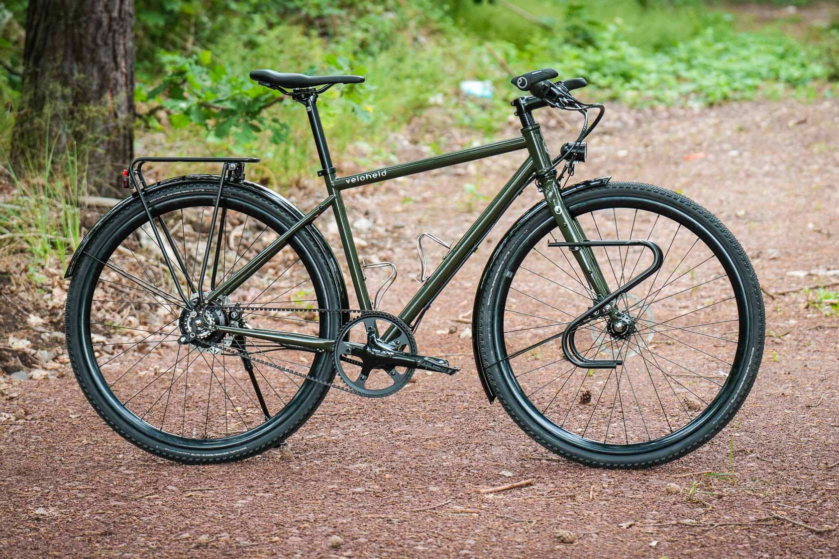 veloheld.alleyX Complete bike with Rohloff hub gears, mudguards and luggage rack as full view on a forest path.