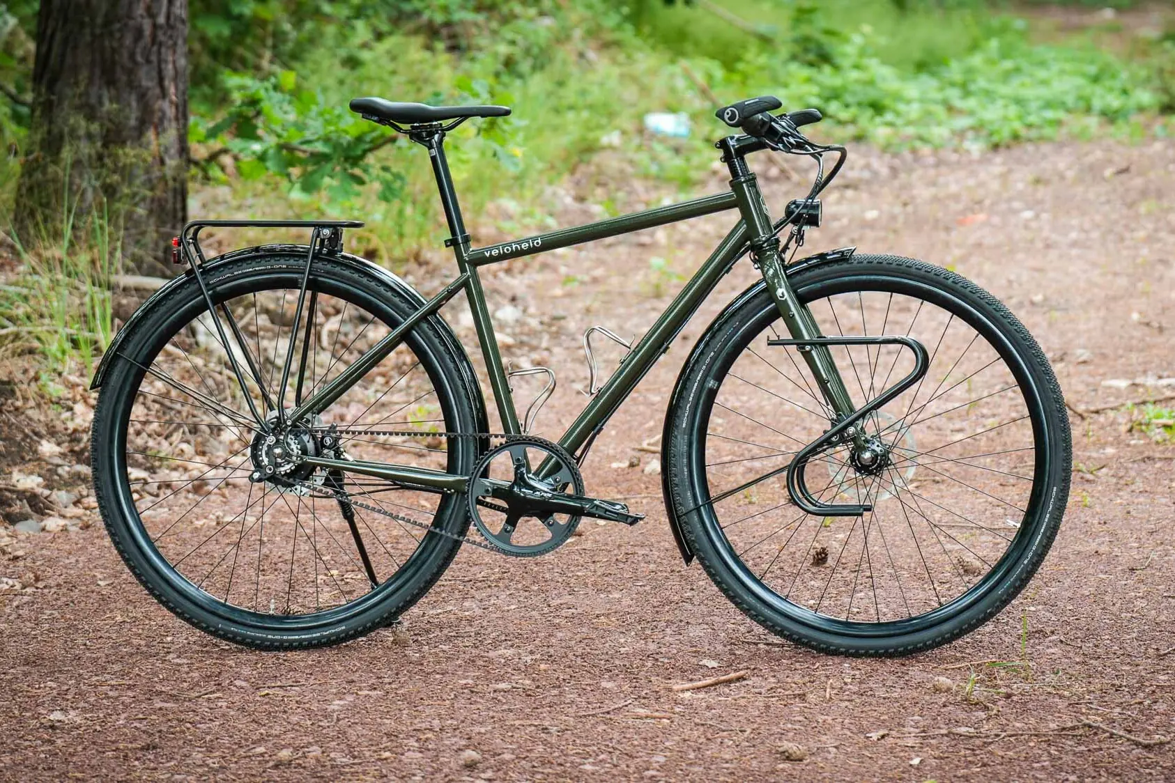 veloheld.alleyX Complete bike with Rohloff hub gears, mudguards and luggage rack as full view on a forest path.