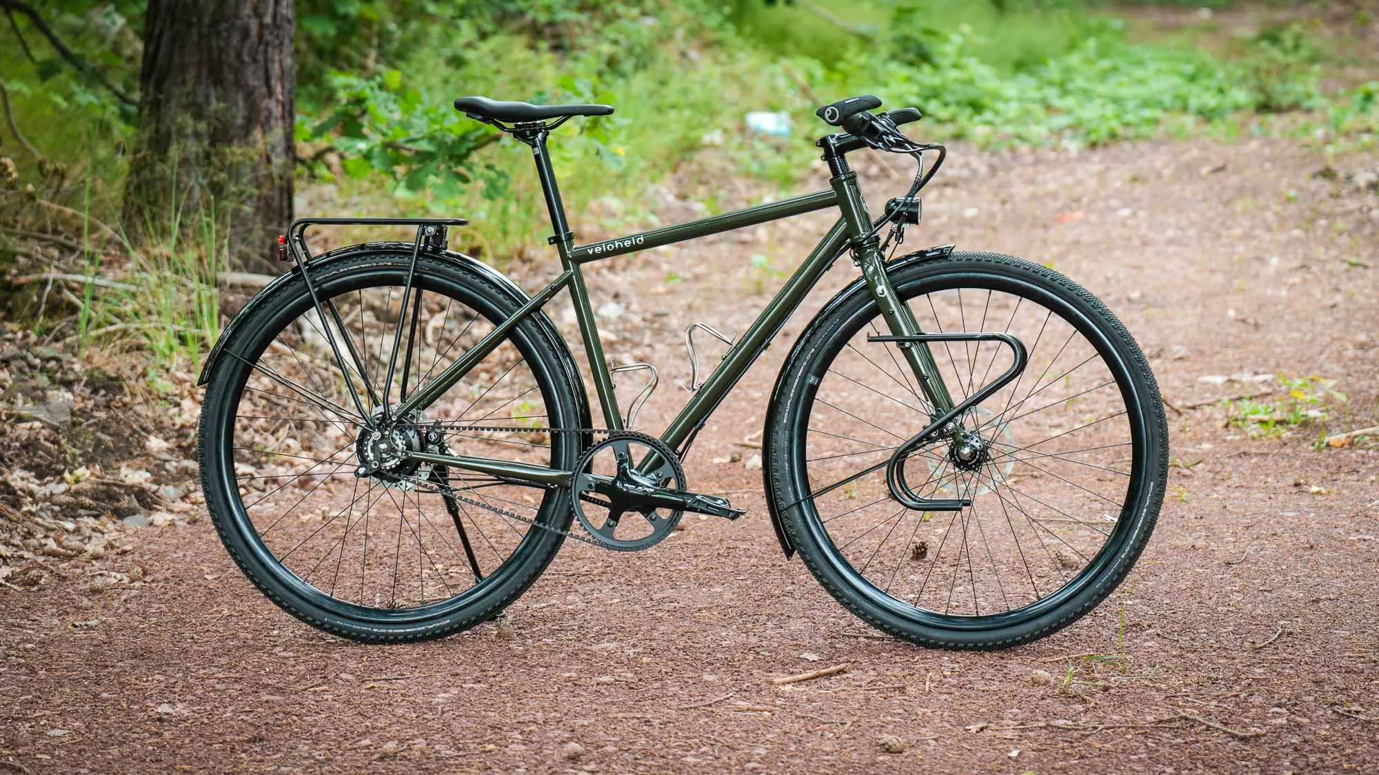 veloheld.alleyX Complete bike with Rohloff hub gears, mudguards and luggage rack as full view on a forest path.